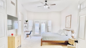 A bedroom with a bed, a desk, a chair, a ceiling fan, and a door leading to a balcony. - Private and Charming Vacation Home near Downton Gilbert - Pool/hot tub/fireplace (Gilbert)