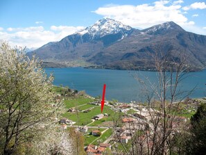 Un paysage montagneux avec un lac, un village et un poteau rouge.