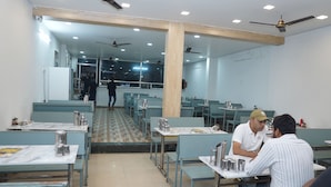 Un comedor con mesas y sillas, una escalera y ventiladores de techo.