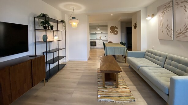 A modern living room with a flat-screen TV, a wooden coffee table, a sofa, and a dining area with a table and chairs. - T2 Bord du Canal du Midi Piscine (Homps)
