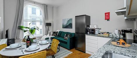 A compact living space with a dining area, kitchenette, and a sofa.