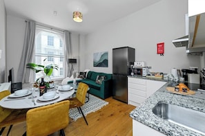 A compact living space with a dining area, kitchenette, and a sofa. - 1 Bed Apt Next to Market Square & Transport Links (Nottingham)