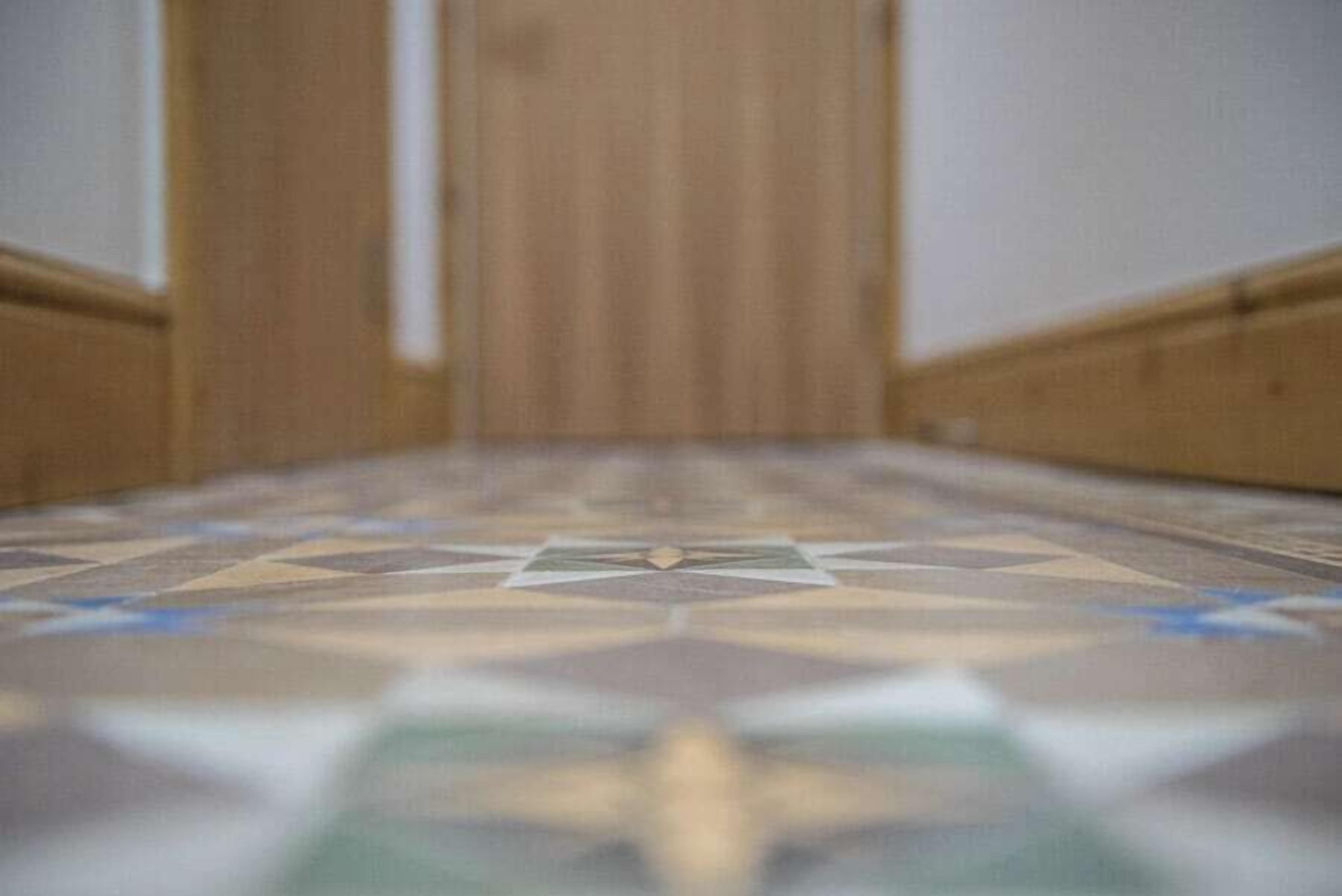 A hallway with a patterned floor leading to a door.