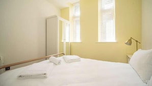 A hotel room with a bed, a bedside lamp, and a window with blinds. - Wow! 1bed Stunning Apt in Victorian Mansion (Nottingham)
