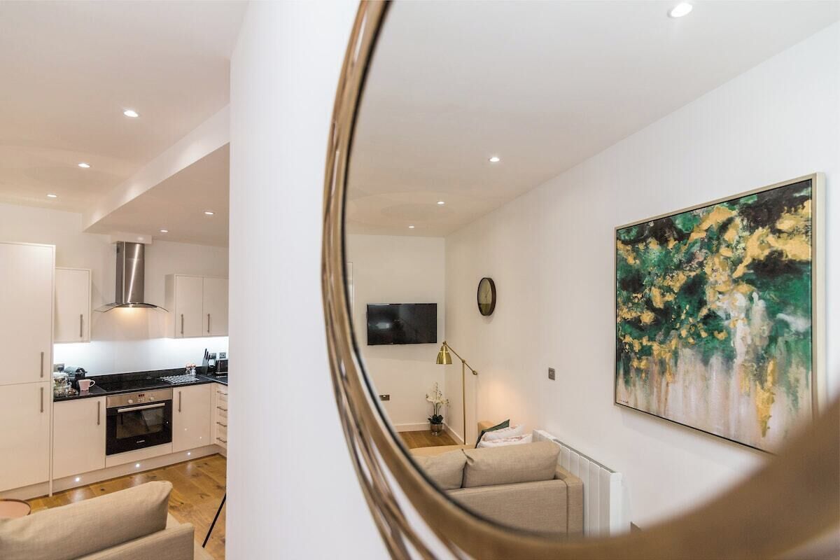 A modern kitchen with white cabinetry, a built-in oven, and a dining area with a table and chairs.