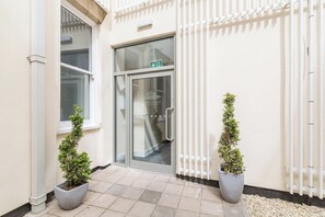 A building entrance with a glass door, potted plants, and a tiled floor. - Lovely 1 Bedroom Apartment at City Centre (Nottingham)