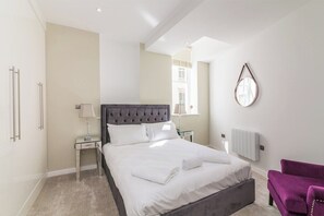 A bedroom with a bed, bedside tables, a chair, a radiator, and a window. - Lovely 1 Bedroom Apartment at City Centre (Nottingham)