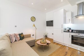 A modern kitchen with white cabinets, a Bosch oven, and a round coffee table with a glass top. - Lovely 1 Bedroom Apartment at City Centre (Nottingham)