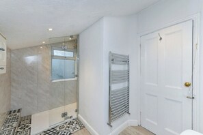 A bathroom with a shower, a towel rack, and a door. - 5-BR Home Featuring Art and Photography Collection (Nottingham)