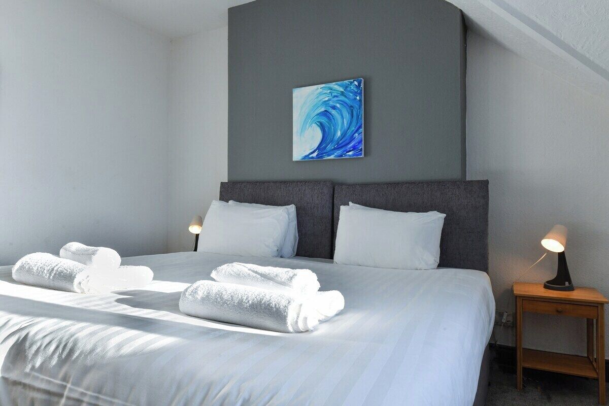 Una habitación de hotel con una cama, dos mesitas de noche y una obra de arte colgada en la pared.