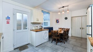 Een compacte keuken met een wasmachine, een eettafel met stoelen en een koelkast.