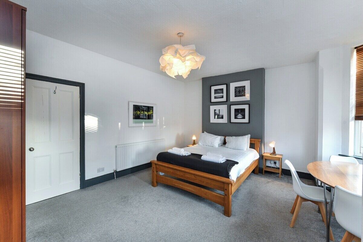 Een slaapkamer met een bed, nachtkastjes, een bureau en stoelen.