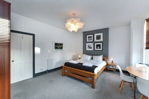 A bedroom with a bed, bedside tables, a desk, and chairs. - 5-BR Home Featuring Art and Photography Collection (Nottingham)