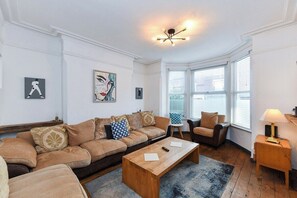 Un salon avec un canapé, des fauteuils, une table basse et une lampe.