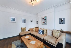 A living room with a sectional sofa, a wooden coffee table, and framed artwork on the walls. - 5-BR Home Featuring Art and Photography Collection (Nottingham)