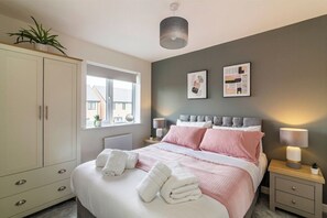 A bedroom with a bed, bedside tables, a wardrobe, a window, and wall art.