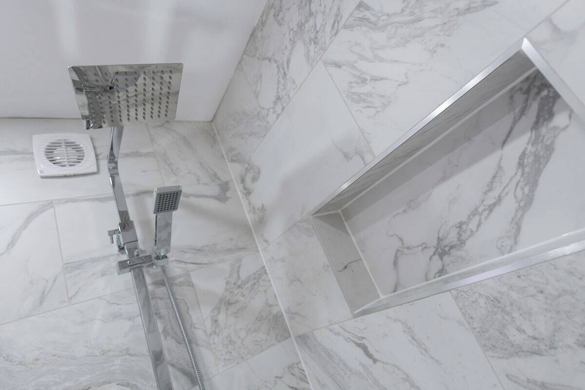 A bathroom with a shower, a toilet, and a vent.