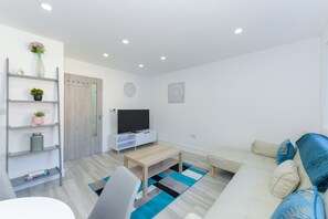 Relax in this stylish space with a comfortable sofa set, flat-screen TV, and shelving unit.