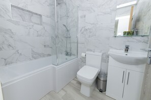 Features a sleek bathroom with a glass-enclosed shower, standalone toilet, and minimalist sink.