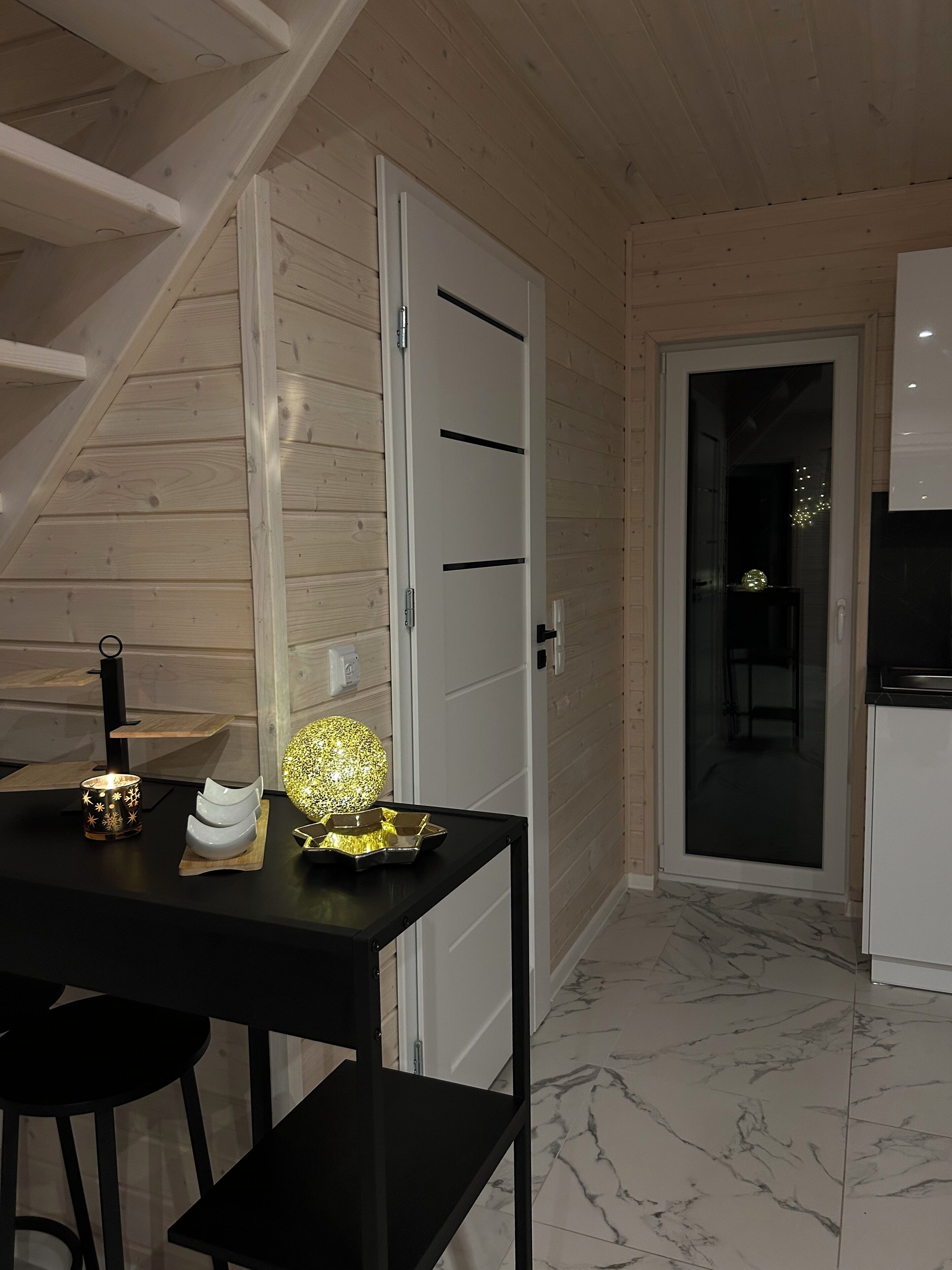 A modern kitchen with a black countertop, white cabinets, and a marble floor.