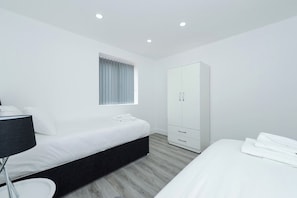 A modern bedroom with a bed, a wardrobe, and a bedside table. - 2-BR Flat w/ Free Parking Near Nottingham (Gedling)