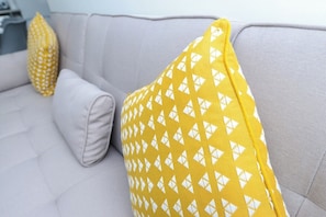 A sofa with two pillows, one plain and one with a geometric pattern.