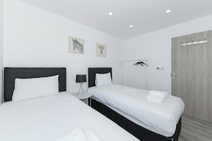 Ein Hotelzimmer mit zwei Betten, einem Kleiderständer und einer Tür.