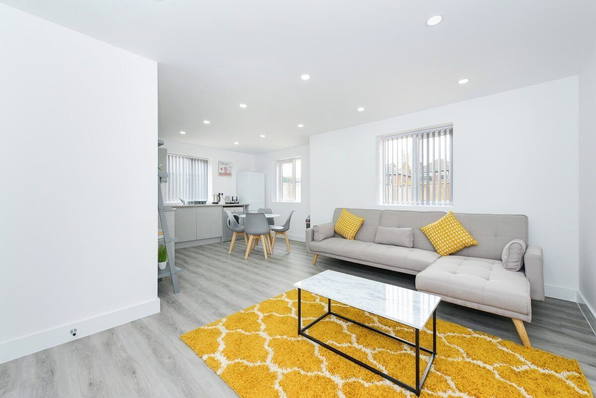 A modern living room with a sofa, coffee table, and yellow rug.