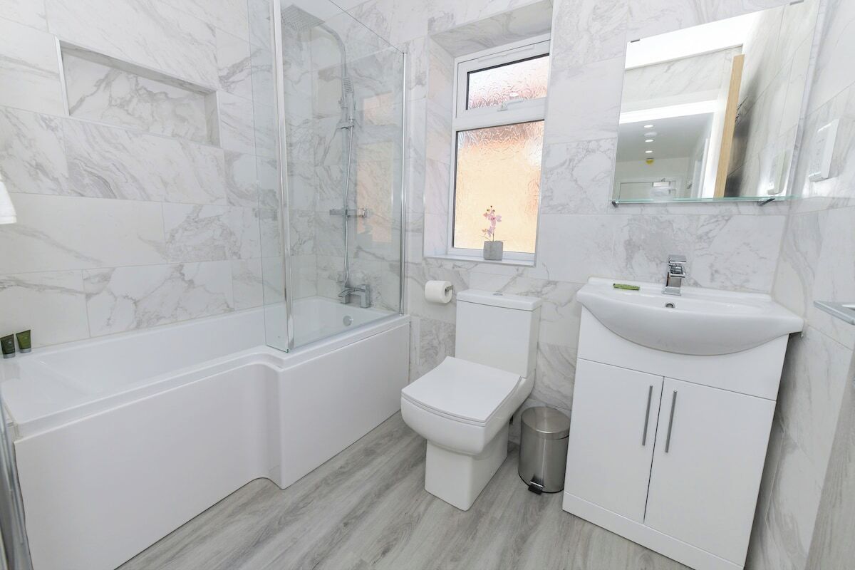 Een badkamer met een douchecabine van glas, een toilet, een wastafel en een spiegel.