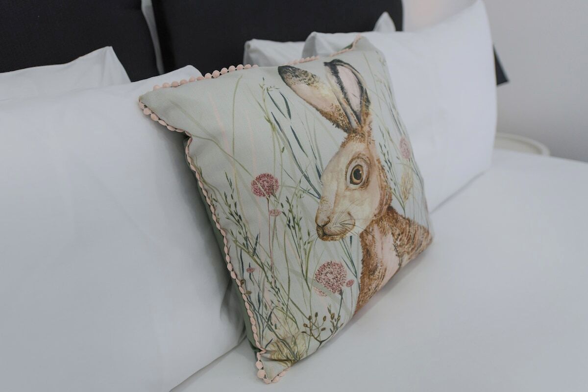 Un oreiller orné d’un motif représentant un lapin, posé sur un lit.