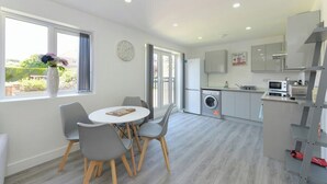 A modern kitchen with a washing machine, a microwave, and a dining area with a round table and chairs. - 2-BR Stay w/ Parking Near Nottingham (Carlton)