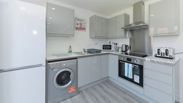 A modern kitchen with a washing machine, microwave, oven, and a toaster. - 2-BR Stay w/ Parking Near Nottingham (Carlton)