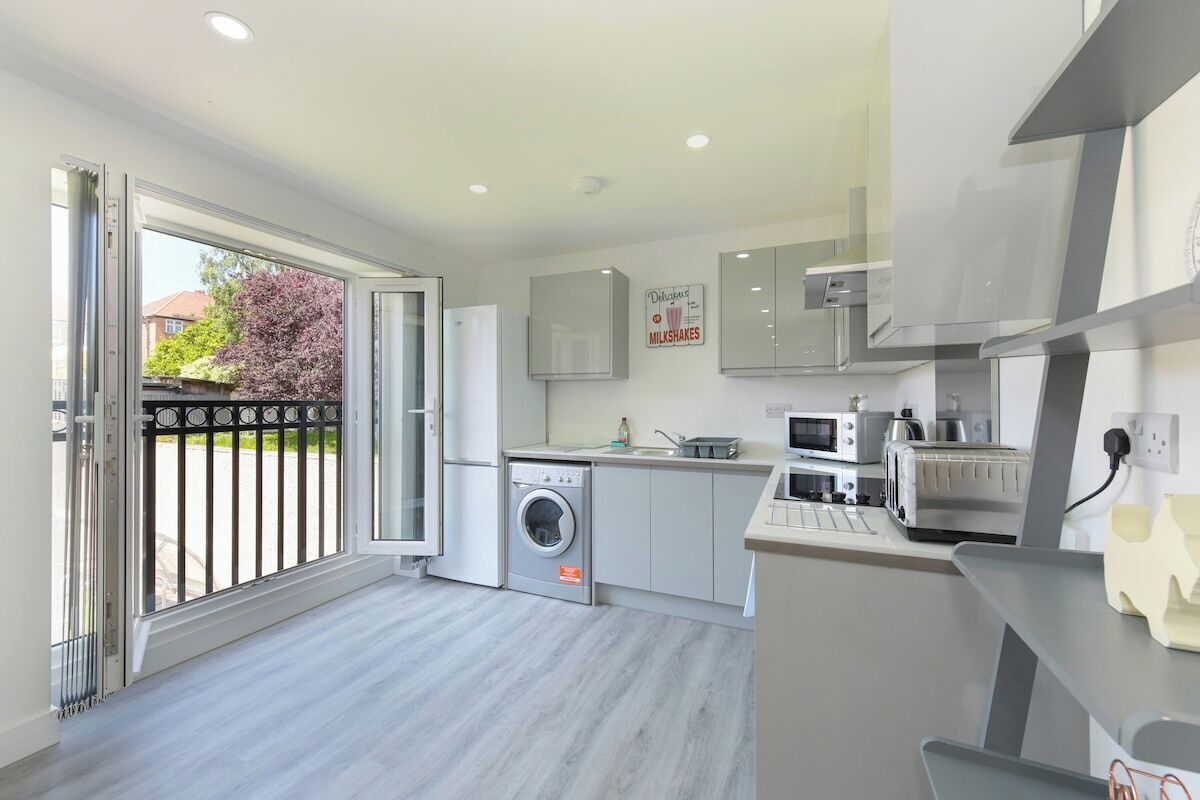 A modern kitchen with a built-in washing machine, a microwave, and a toaster.