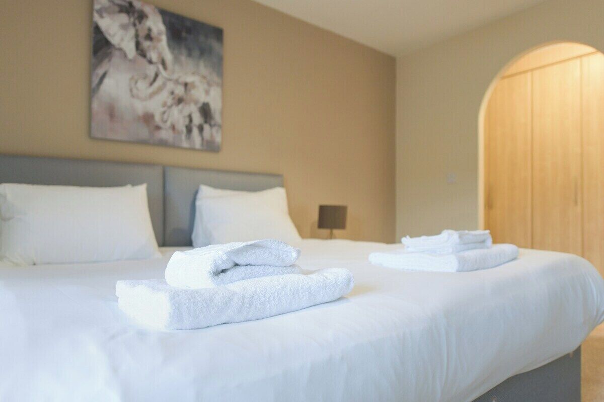 A hotel room with a large bed, a painting on the wall, and a wooden door.