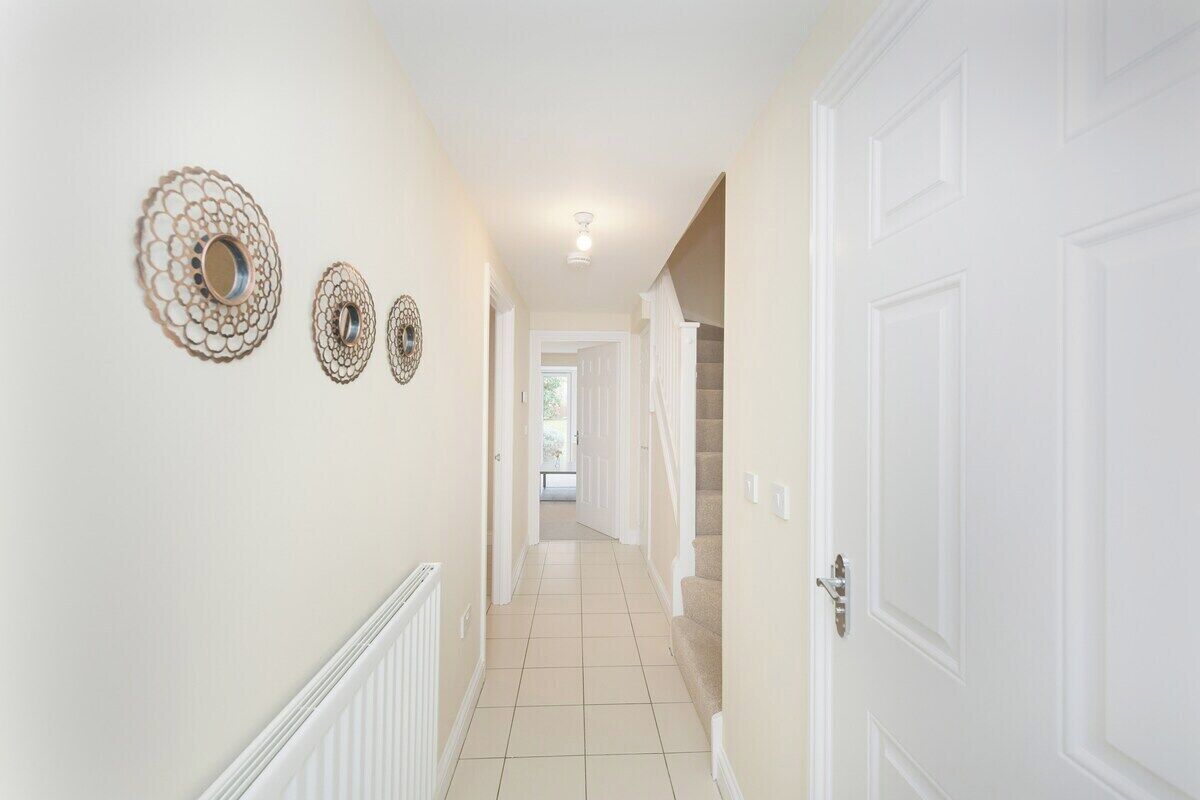 A hallway with white walls, a tiled floor, and three decorative wall sconces.