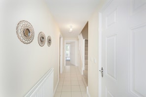 A hallway with white walls, a tiled floor, and three decorative wall sconces.