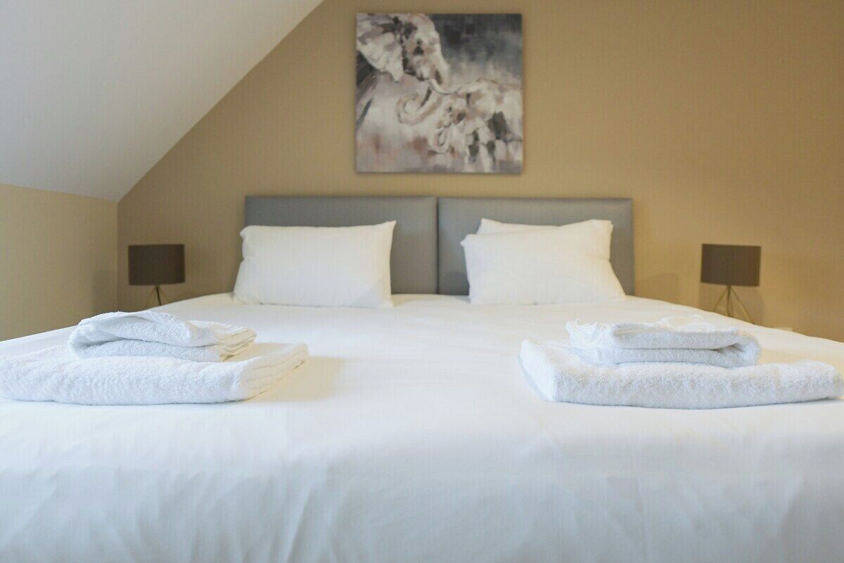 A hotel room with a large bed, two nightstands, and a painting on the wall.