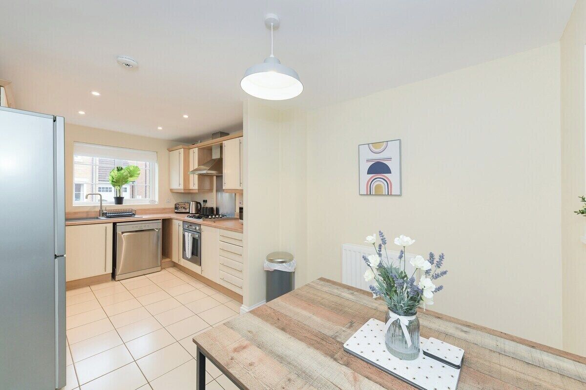 A modern kitchen with a wooden countertop, stainless steel appliances, and a hanging light fixture.