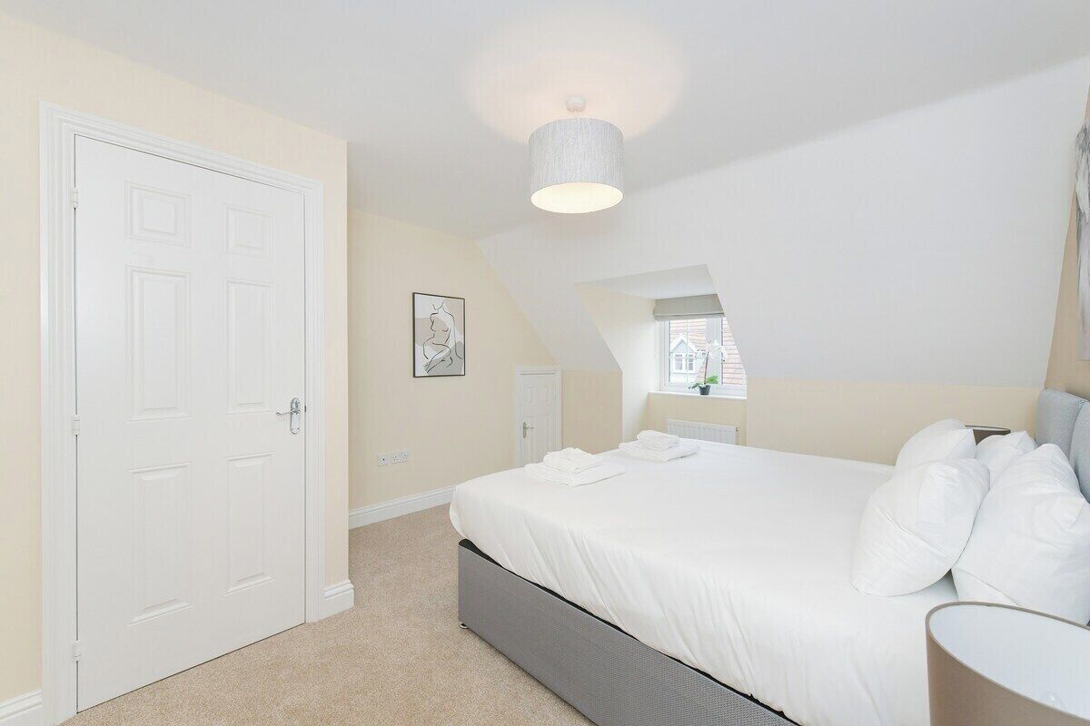 A bedroom with a bed, a door, a ceiling light, and a window.