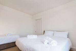 A hotel room with two beds, white bedding, and neatly folded towels.
