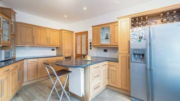 A kitchen with wooden cabinets, a stainless steel refrigerator, and a bar stool.