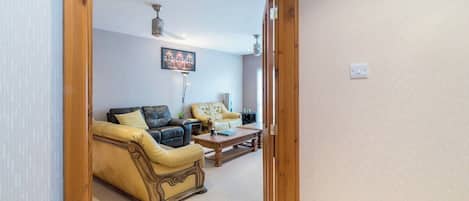 A living room with a sofa, armchairs, a coffee table, and a painting on the wall.