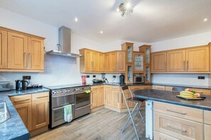 A modern kitchen with wooden cabinets, stainless steel appliances, and a black countertop.