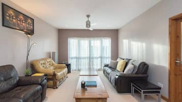 A living room with leather sofas, a wooden coffee table, and a ceiling fan.