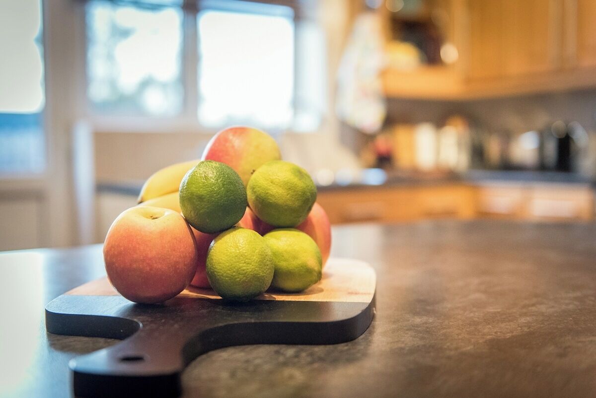 Una tabla de cortar con frutas sobre una encimera de cocina.
