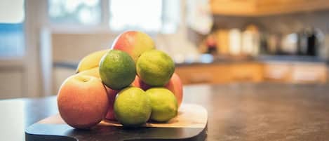 A cutting board with fruits on a kitchen counter.