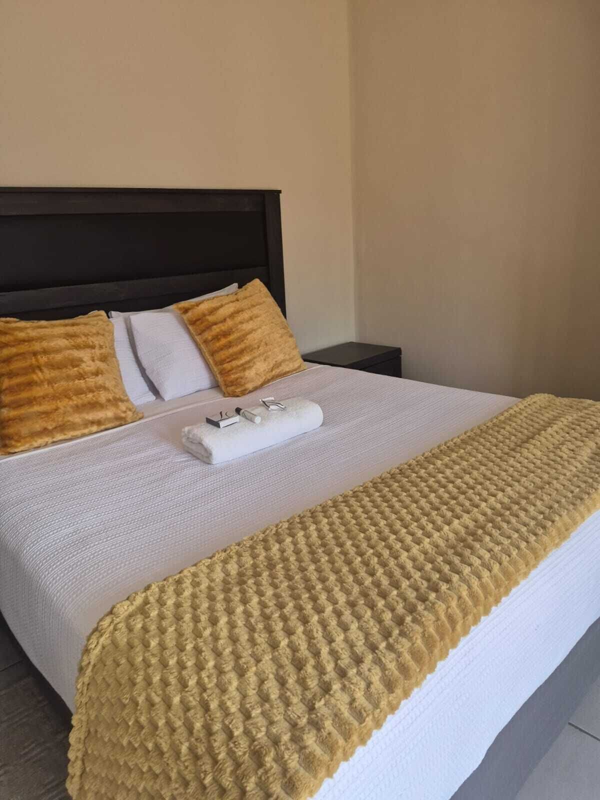 A neatly made bed with a white comforter, two pillows, and a textured blanket.