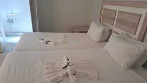 A hotel room with two beds, each with neatly folded towels and toiletries. - Jate Guest House (Maseru)