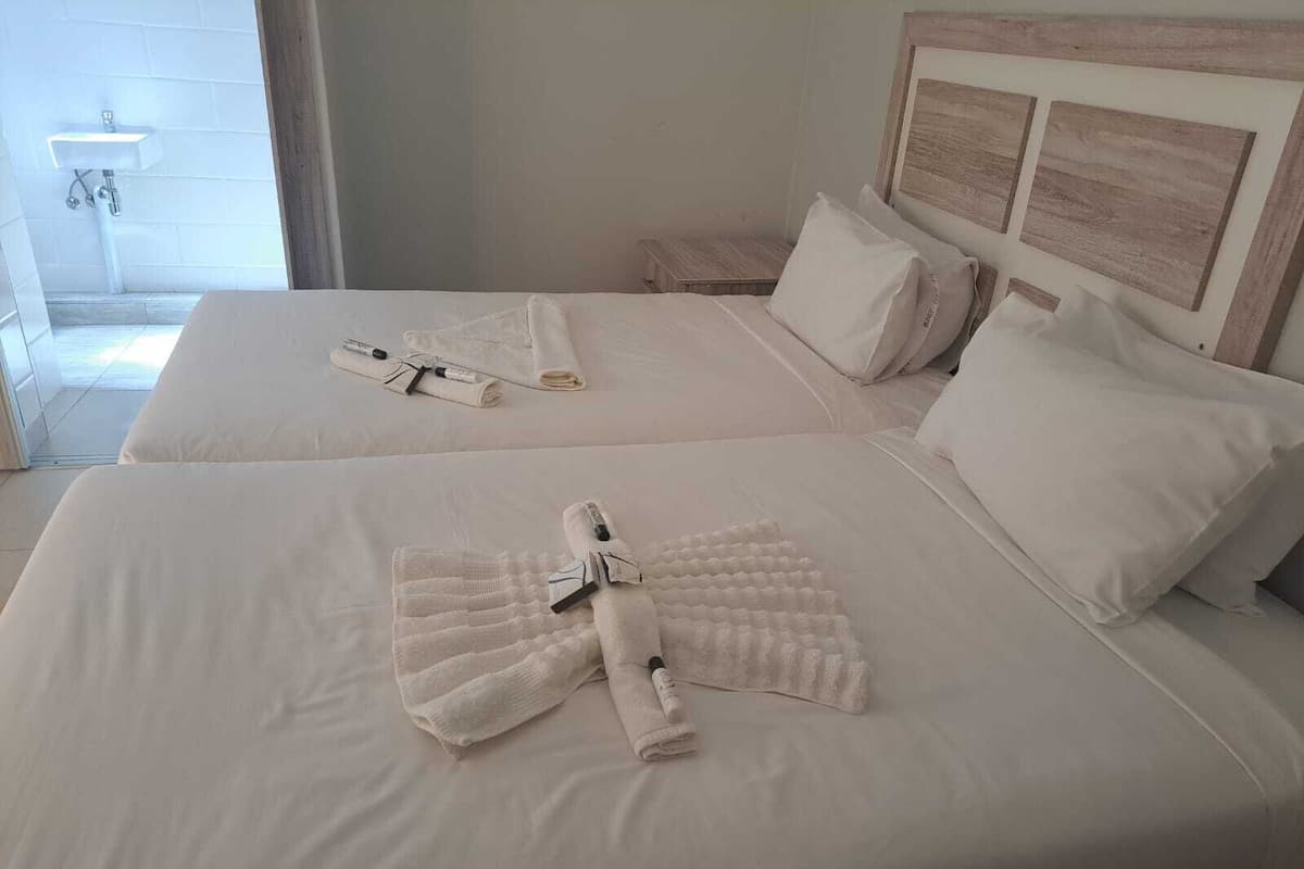 A hotel room with two beds, each with neatly folded towels and toiletries.