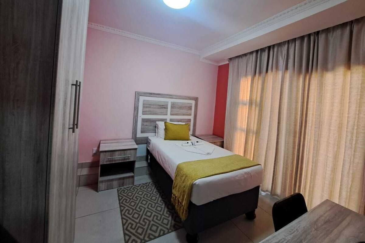 A bedroom with a bed, bedside tables, a desk, and a chair.